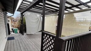 A wooden deck with a pergola structure, a covered area with a white tarp, and a green trash bin. - Newly remodeled home on a quiet street with a large yard. (Salt Lake City)