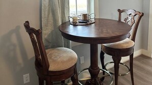 A dining table with two chairs, a window with a curtain, and a power outlet on the wall. - Red Brush Cottage Property (Elkton)