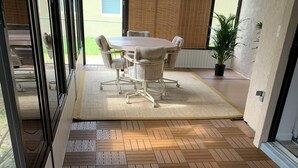 Een kamer met een visgraatparketvloer, een ronde tafel met stoelen en een potplant.
