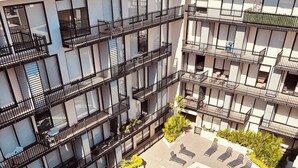 Ett hotell med flera våningar, en central pool omgiven av solstolar och en liten trädgårdsdel.