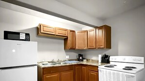 Una cocina con armarios de madera, un refrigerador blanco, una estufa y un microondas.