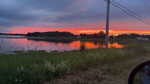 Un atardecer sobre un lago con orilla de hierba y un poste de electricidad.