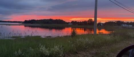 Un atardecer sobre un lago con orilla de hierba y un poste de electricidad.