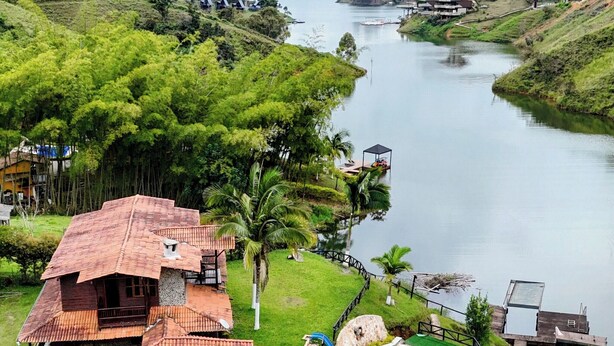 Un resort sul fiume con piscina, edifici in legno e vegetazione rigogliosa.