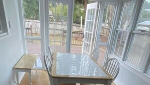 A dining area with a glass-top table and four chairs, large windows, and a wooden deck visible through the glass doors. - 227 Country House of vacation /Eustis (Eustis)