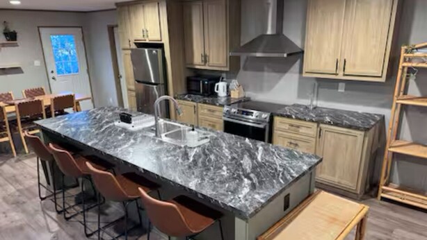 A modern kitchen with a marble island, wooden cabinets, and stainless steel appliances.