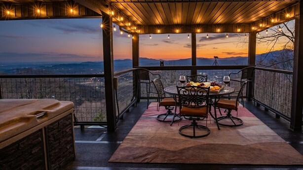 Eine überdachte Terrasse im Freien mit Esstisch, Grill und schöner Aussicht.