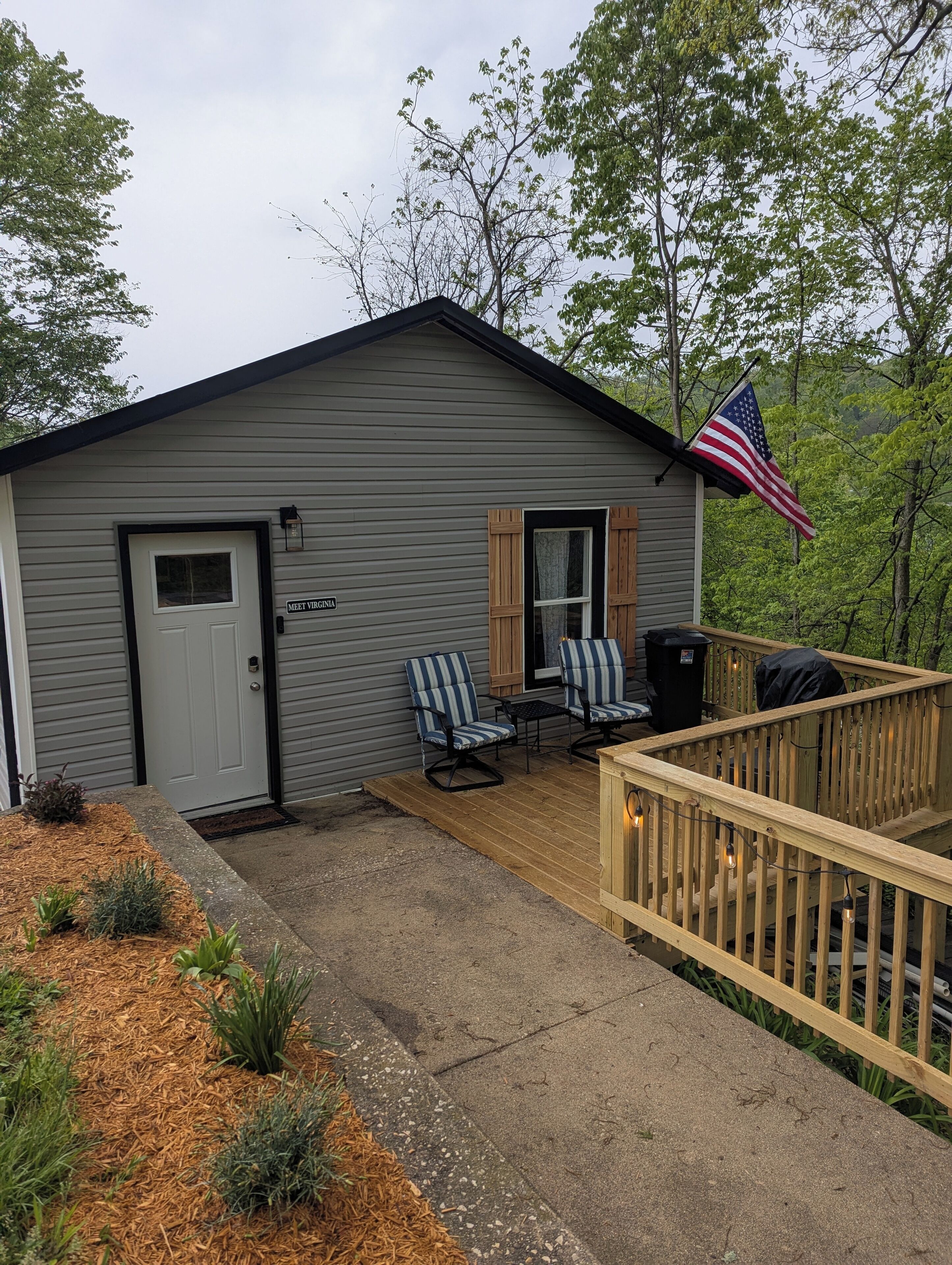 Eine kleine Holzhütte mit einer Veranda, zwei Stühlen und einer amerikanischen Flagge.