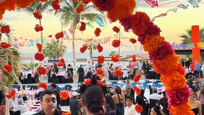 Evento ao ar livre com um arco decorado e uma multidão de pessoas.