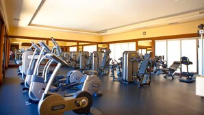 Uma academia com diversos equipamentos de exercício, janelas amplas e teto alto.
