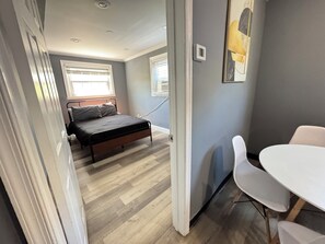 Une chambre à coucher avec un lit, une table de chevet, une chaise et une fenêtre.
