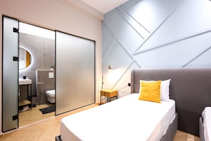 A modern hotel room with a bed, bedside table, and a wall-mounted lamp. - Grandstay Central in Durr s (Durrës)