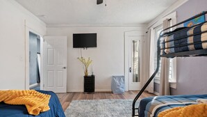A bedroom with two beds, a TV, a dresser, and a window with curtains. - Mara Retreat: Unit B: Fire Pit-Grill-Groups-Patio-Games-Ping Pong Table  (Birmingham)