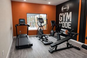 A gym with a treadmill, elliptical, and weight bench. - Elegant Home near Disney - pool - free parking (Kissimmee)