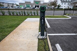 An electric vehicle charging station in a parking lot with a building in the background. - Elegant Home near Disney - pool - free parking (Kissimmee)