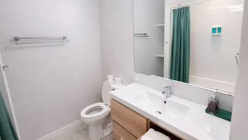 A bathroom with a toilet, sink, mirror, and towel storage.