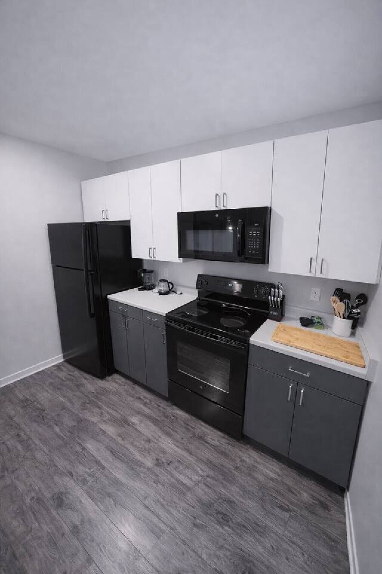Una cocina moderna con un refrigerador negro, microondas, estufa y horno, además de una cafetera y utensilios.