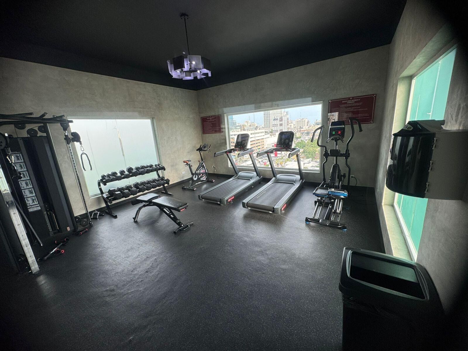Un gimnasio con cintas de correr, máquinas de pesas y mancuernas.