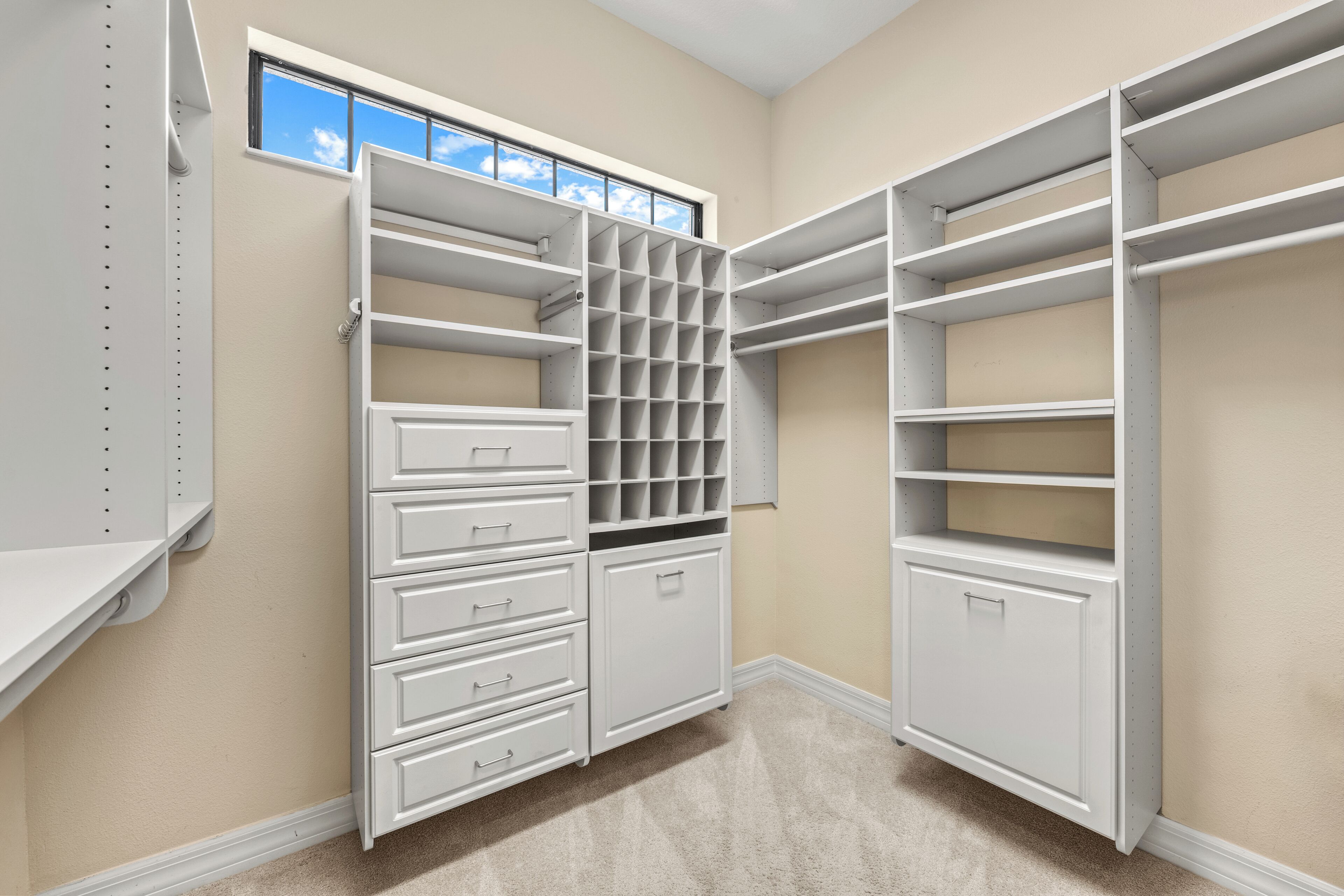 A walk-in closet with open shelving, drawers, and a window.
