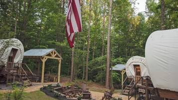 Ein Campingplatz mit überdachten Bereichen, einem Fahnenmast mit der US-Flagge und einer Feuerstelle.
