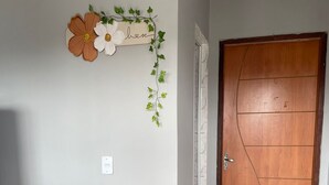 Une pièce avec une porte en bois, une étagère fixée au mur et un panneau décoratif orné de fleurs et du mot « croire ».