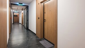 Een hotelgang met houten deuren, een zwarte marmeren vloer en een modern armatuur.