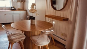 Ein runder Holztisch mit zwei Stühlen, einem Topf mit einer Orchidee und einem Spiegel an der Wand.