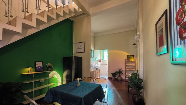 Ein Essbereich mit einem für zwei Personen gedeckten Tisch, einer grünen Wand und einer Treppe.