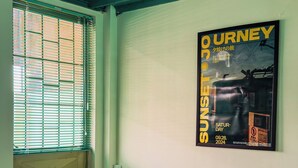 Ein Zimmer mit einem Bett, einer roten Bank, einem Fenster mit Jalousien und einem Poster an der Wand.