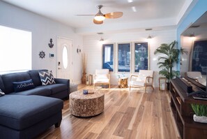 Ein modernes Wohnzimmer mit einem dunkelblauen Sofa, einem runden Holztisch und zwei weißen Sesseln.