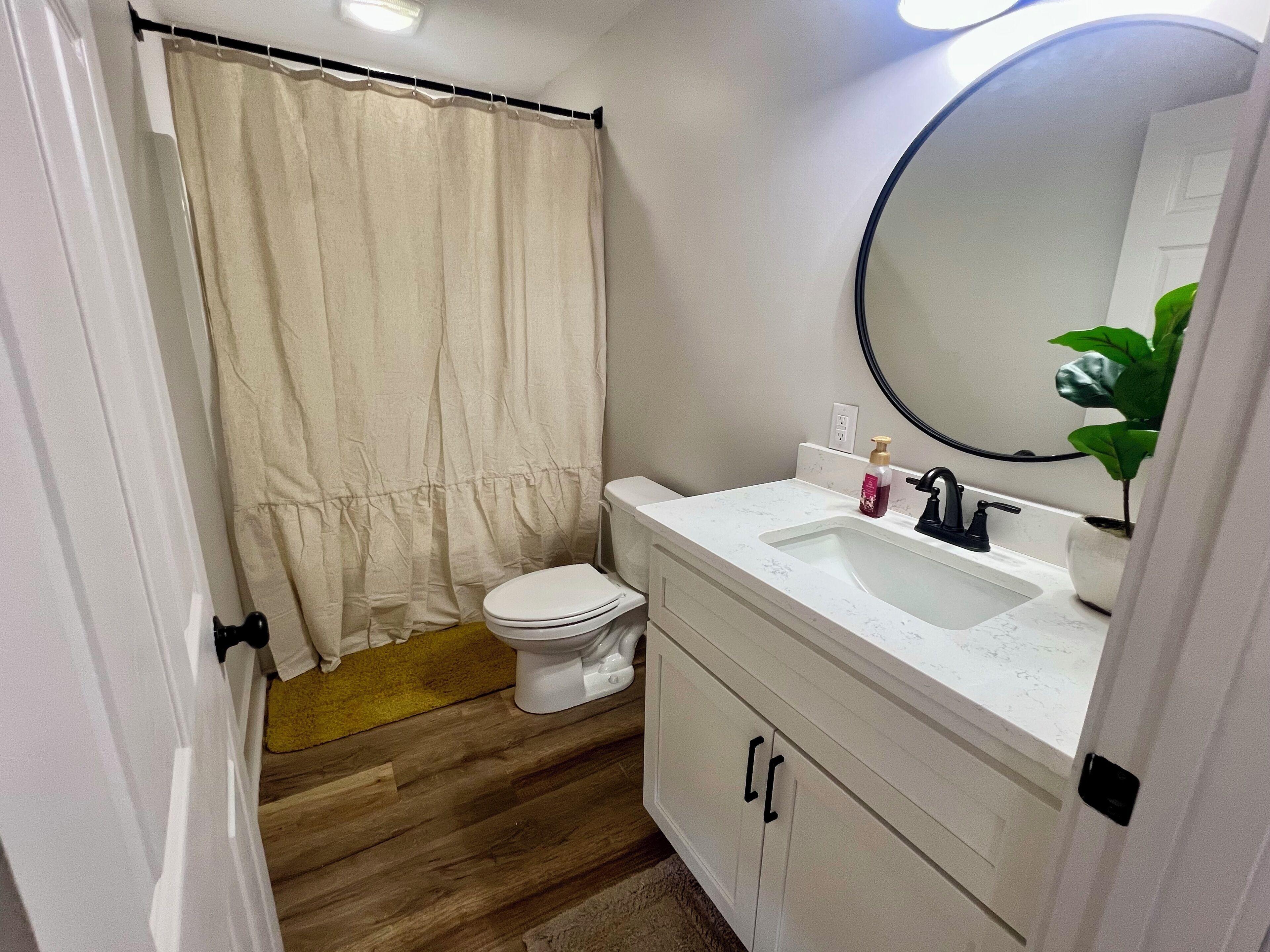 Un baño con inodoro, lavamanos, espejo y cortina de ducha.