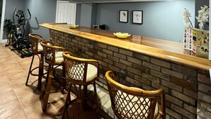 A bar area with a brick counter, three wicker bar stools, and a ceiling light. - Beautiful basement (Wilmot)