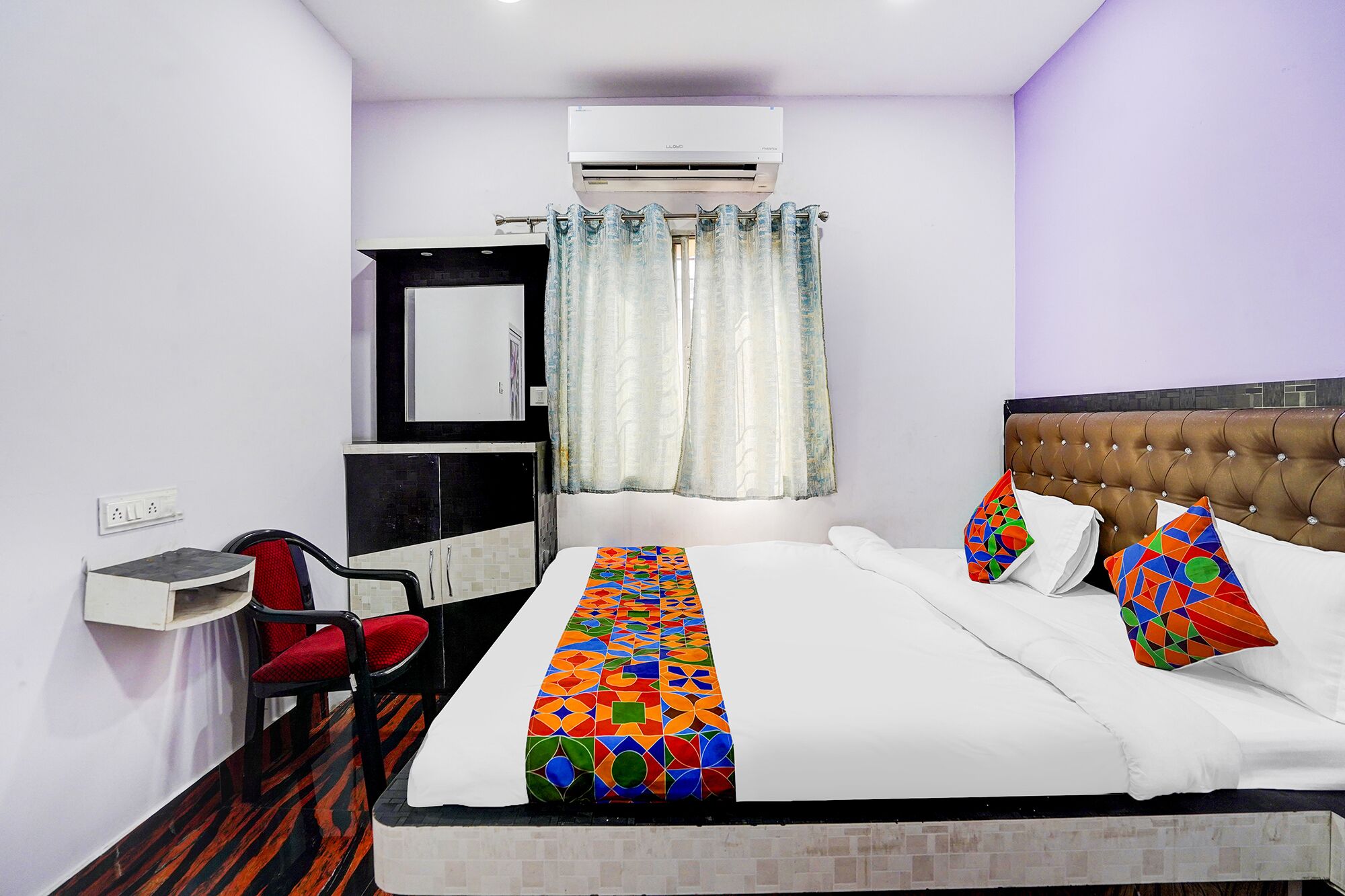 Una habitación de hotel con cama, escritorio, silla y equipo de aire acondicionado.