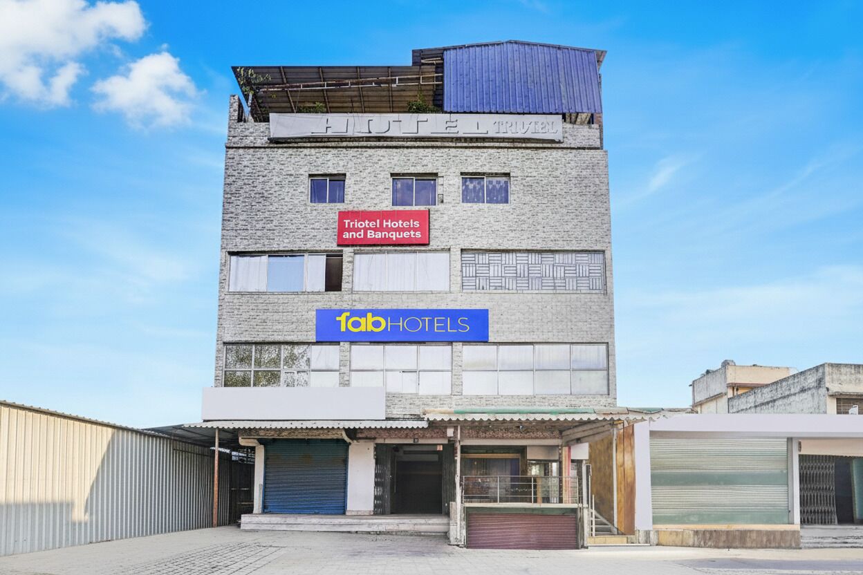 Un edificio de varios pisos con señalización para 'Triotel Hotels and Banquets' y 'Tab Hotels'.