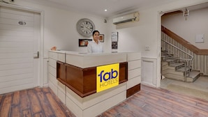 En receptionsdisk med et ur, en trappe og et skilt for 'fab hotels'.