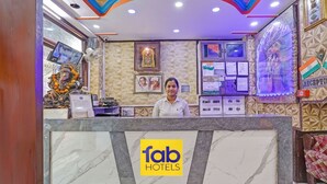 A hotel reception desk with a marble counter, a sign reading "fab hotels", and various framed pictures and documents on the wall. - Fabhotel Kg Palace (New Delhi)