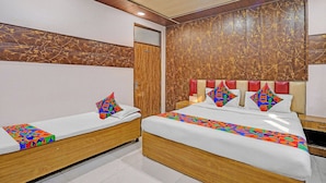 A hotel room with two beds, each with a colorful geometric-patterned bedspread and pillows. The room features wooden paneling on the walls and a wooden headboard. - Fabhotel Kg Palace (New Delhi)