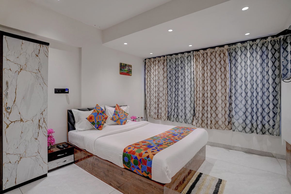 Un dormitorio moderno con una cama, una mesita de noche, un aparador y una ventana con cortinas estampadas.