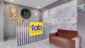 Uma área de recepção de hotel, com balcão, relógio e sofá.