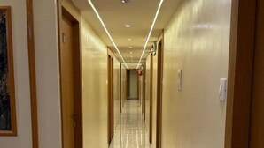 A hotel hallway with a marble floor, wooden doors, and recessed lighting. - Fabhotel Sahara Inn (Mumbai)