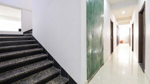 Ein moderner Hotelkorridor mit einer Marmortreppe, einer grünen Marmorwand und einer langen Diele zu den Zimmern.