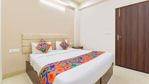 Ein Hotelzimmer mit einem Bett, einem Nachttisch, einer Holztür und einer Deckenleuchte.
