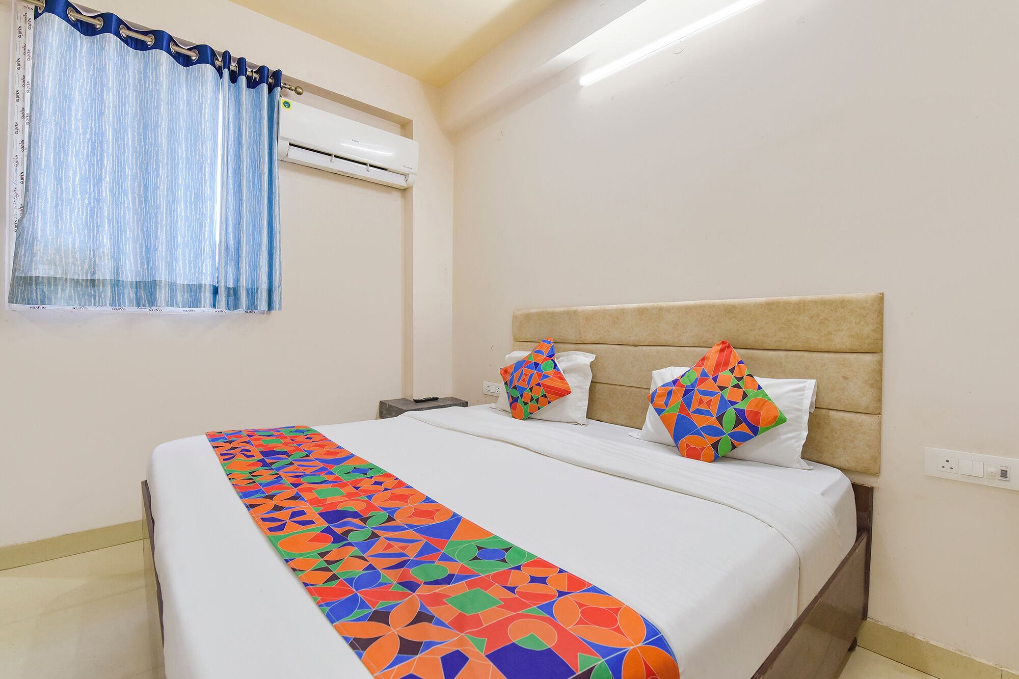 Ein Hotelzimmer mit einem Bett, einem Vorhangfenster, einer Klimaanlage und einem Nachttisch.