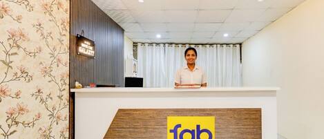 A hotel reception desk with a floral wallpaper design and a sign reading "fab hotels".
