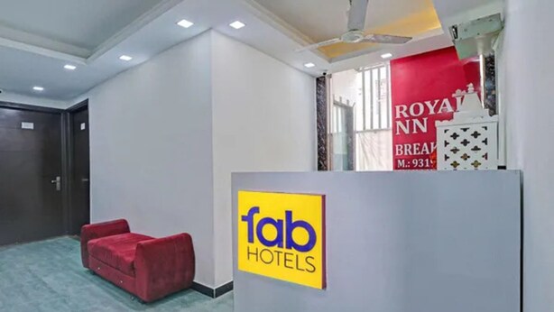 A hotel reception area with a red sofa, a 'fab hotels' sign, and a 'ROYAL NN' sign in the background. - Fabhotel The Royal Inn I (New Delhi)