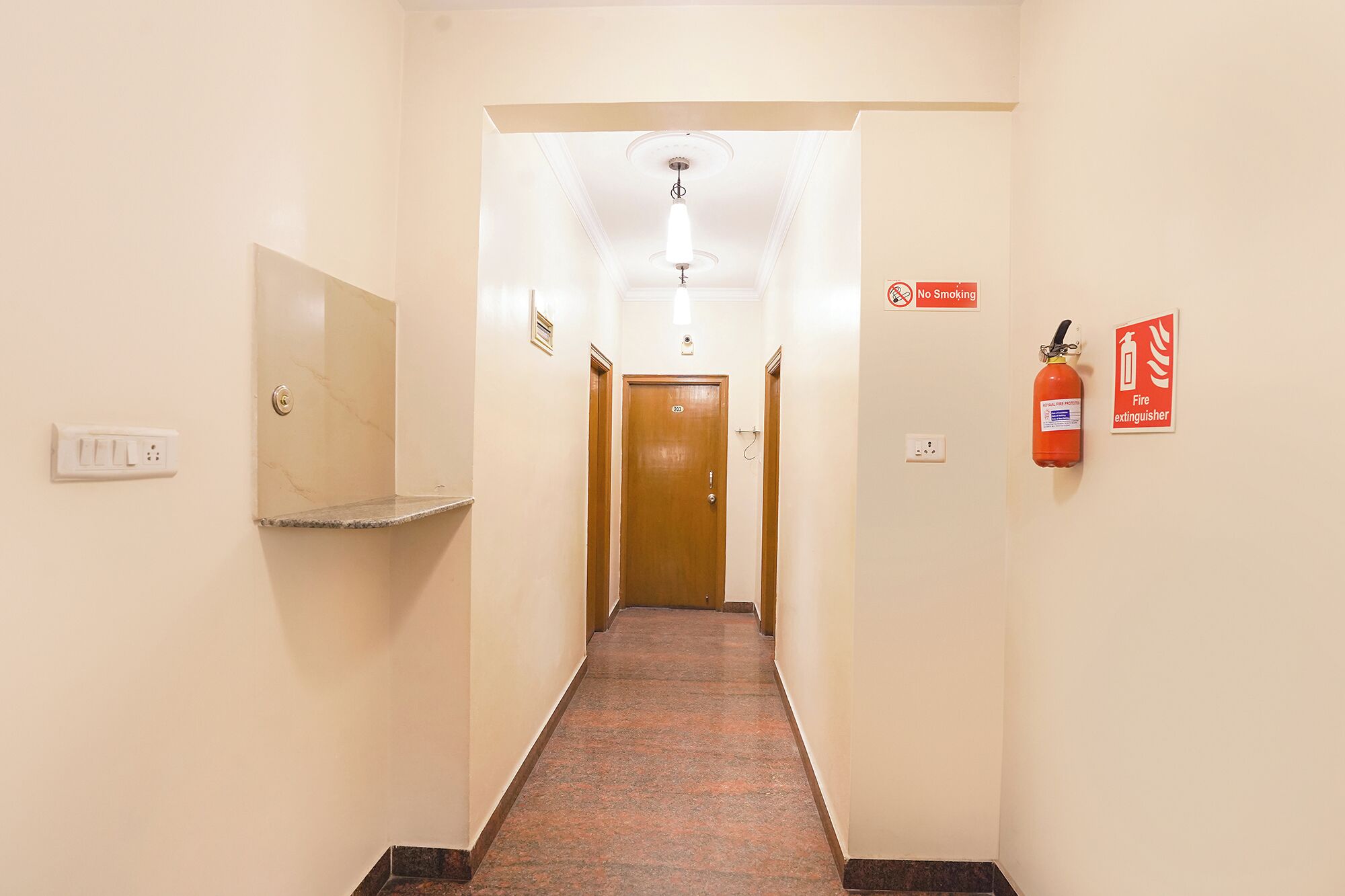 A hotel hallway with a marble counter, a fire extinguisher, and a "No Smoking" sign.