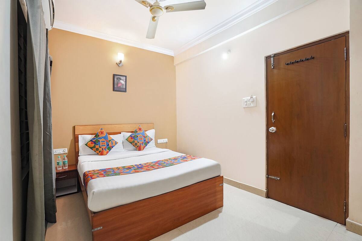 A bedroom with a wooden bed, a ceiling fan, a wall-mounted light, and a door.
