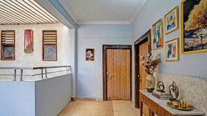A hallway with a wooden door labeled "100C", a small framed picture on the wall, and a console table with decorative items. - Fabhotel Sandalwood Vibes (Bhopal)