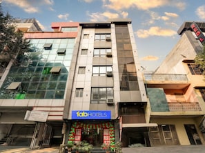 A multi-story building with a sign for 'fabHOTELS' on the ground floor. - Via Red Leaf Stay (New Delhi)