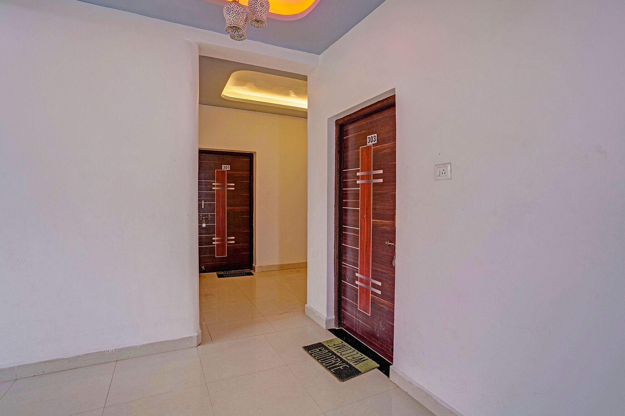 A hallway with two doors, one marked 301 and the other 303, leading to a room.